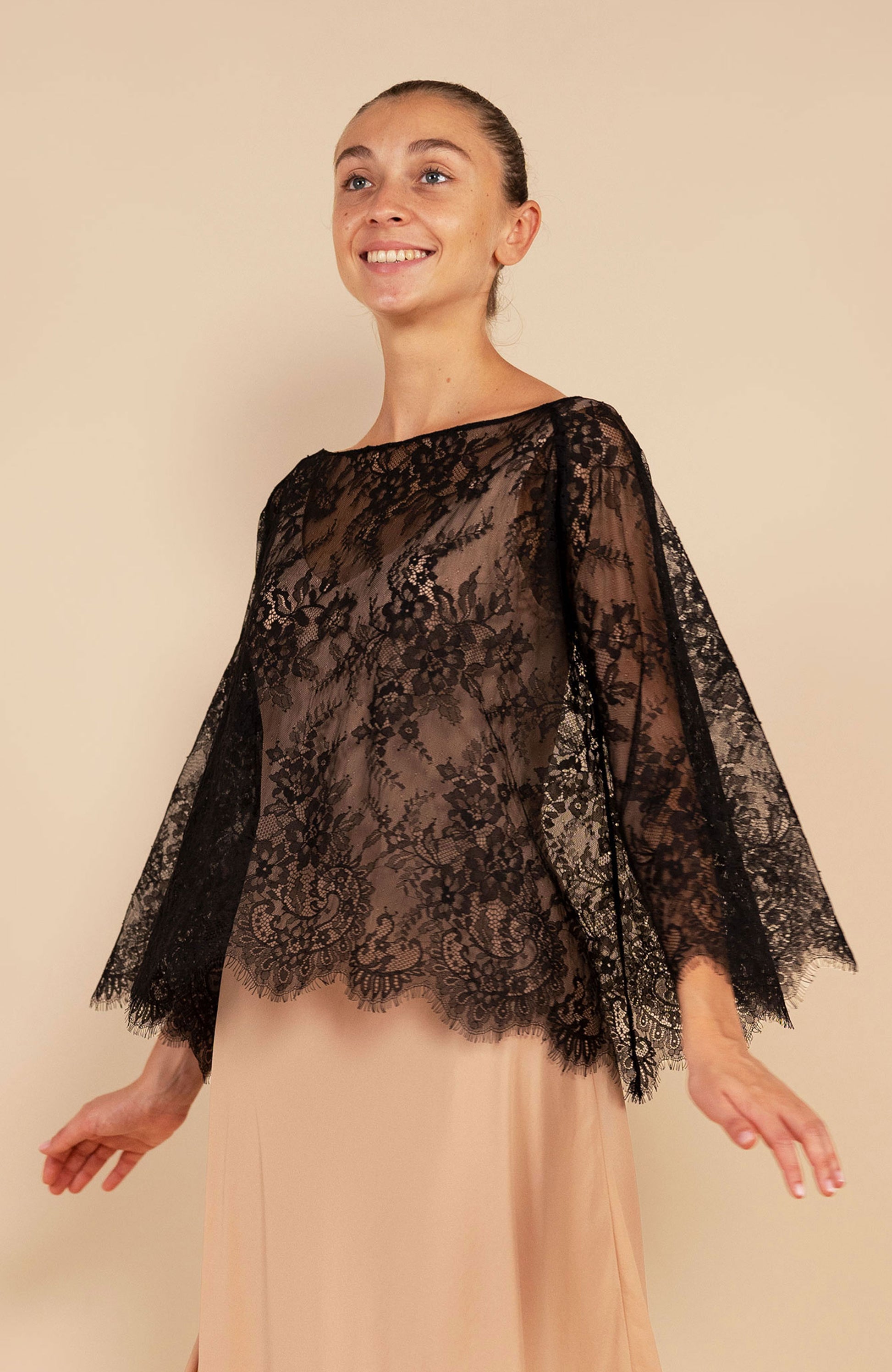 Maglia di pizzo scura indossata al vento sopra un abito chiaro